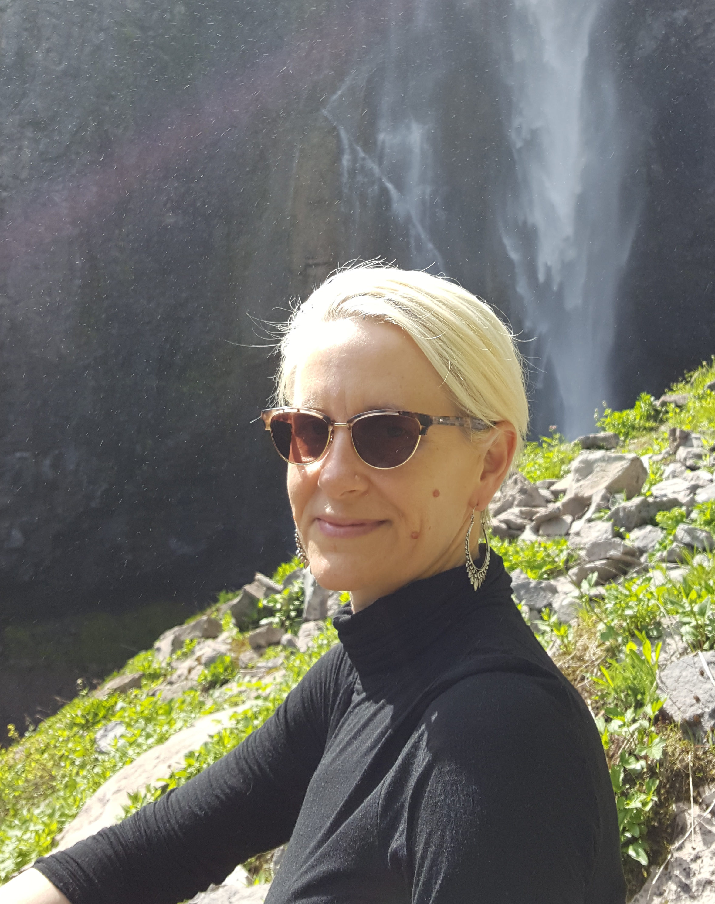 Alex Baker sitting at a waterfall at Mt. Rainer